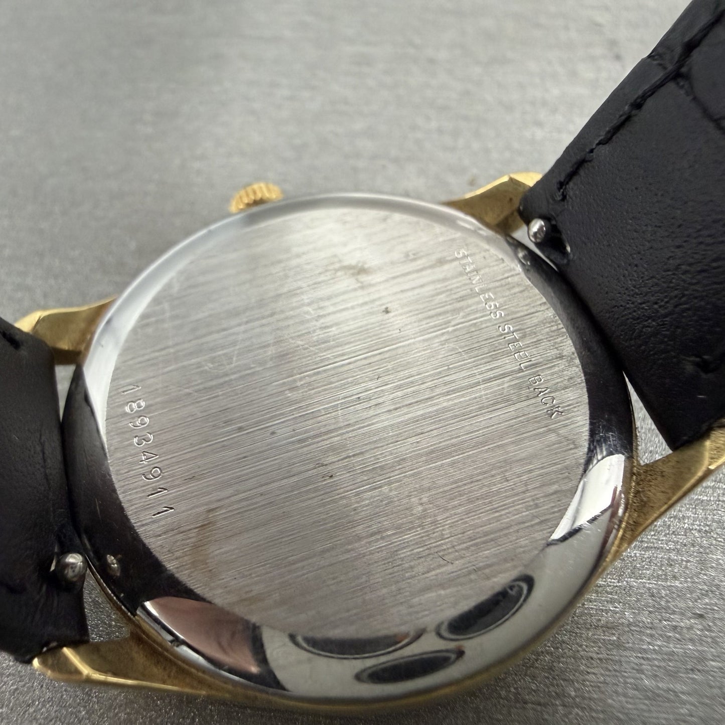 Close-up of vintage wristwatch stainless steel back with serial number and black leather strap