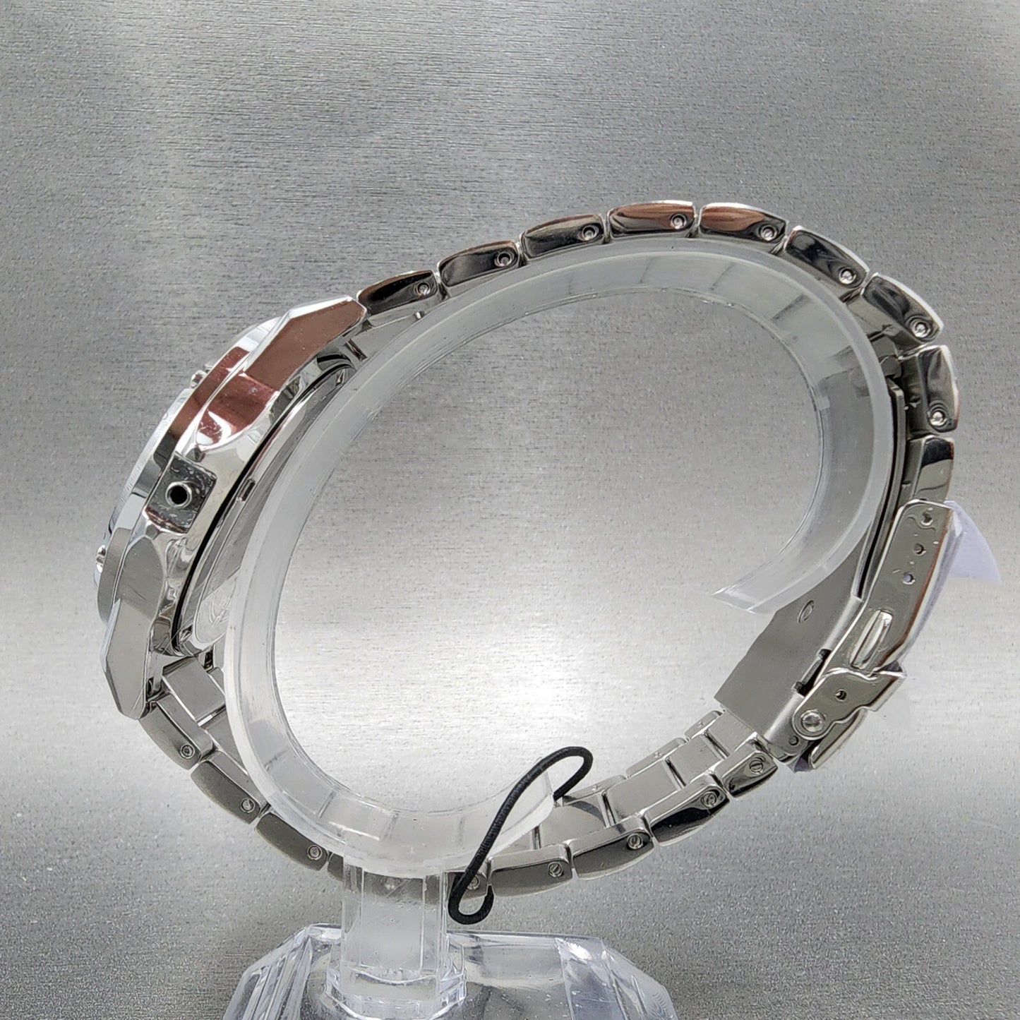 Silver stainless steel watch bracelet on display stand against gray background