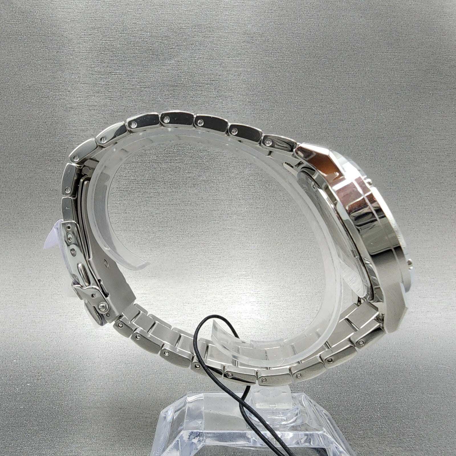 Stainless steel wristwatch side view on display stand, silver metal watch band