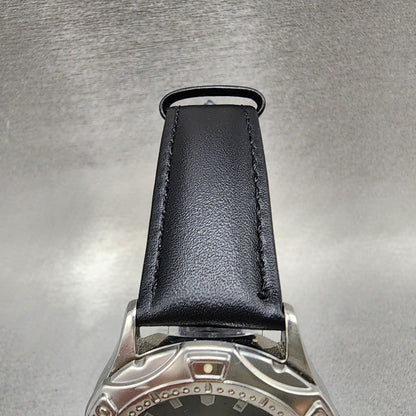 Black leather watch strap with stainless steel case on metallic background