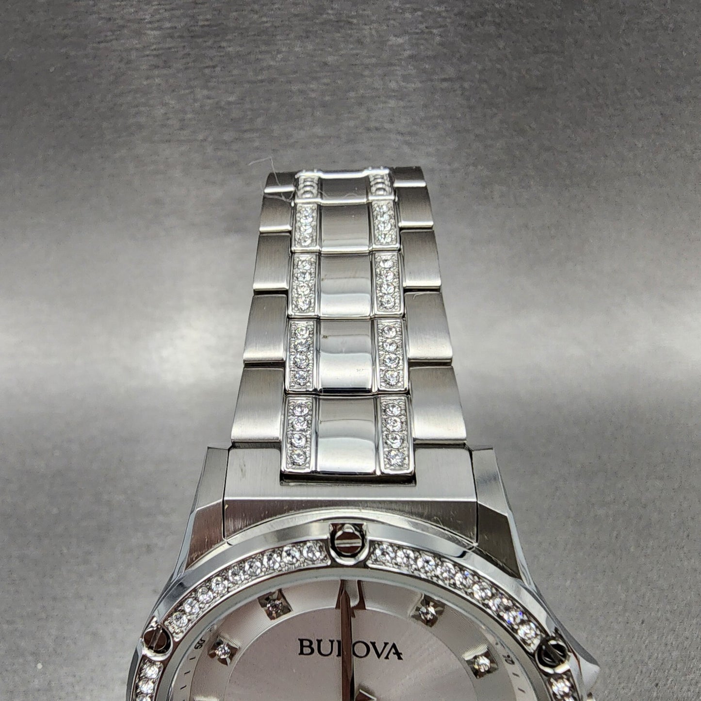 Bulova silver stainless steel watch with crystal-accented band and bezel, close-up view