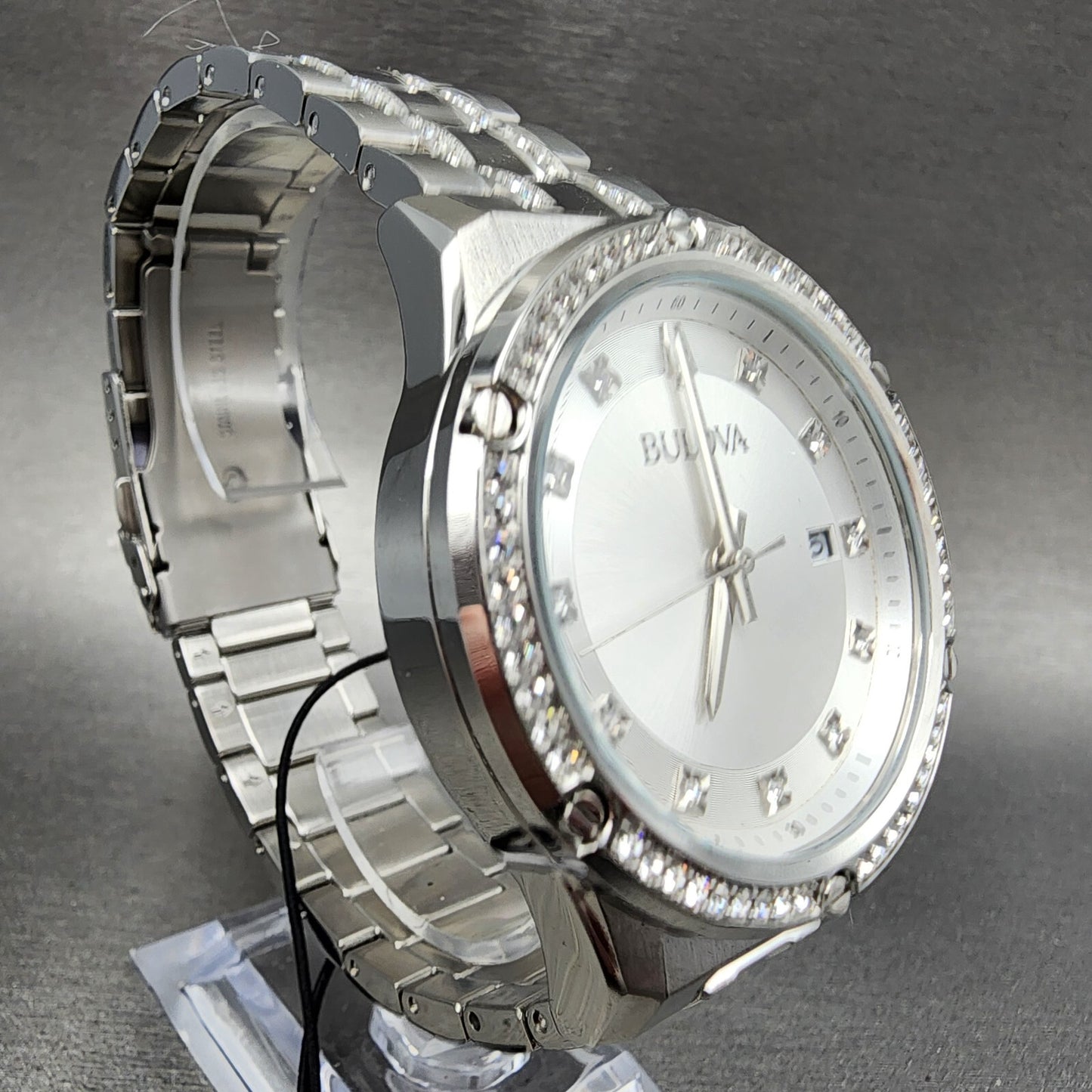 Silver Bulova wristwatch with diamond accents, metal band, and white dial on display stand