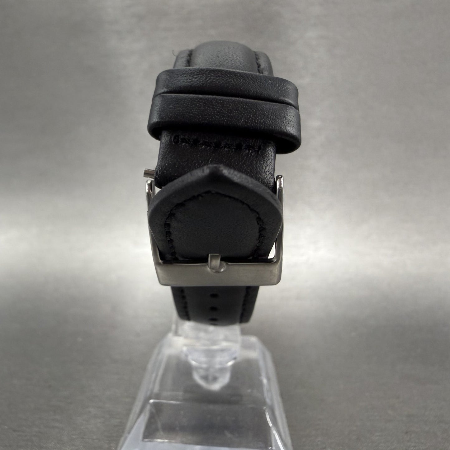 Black leather watch strap with silver buckle on clear display stand