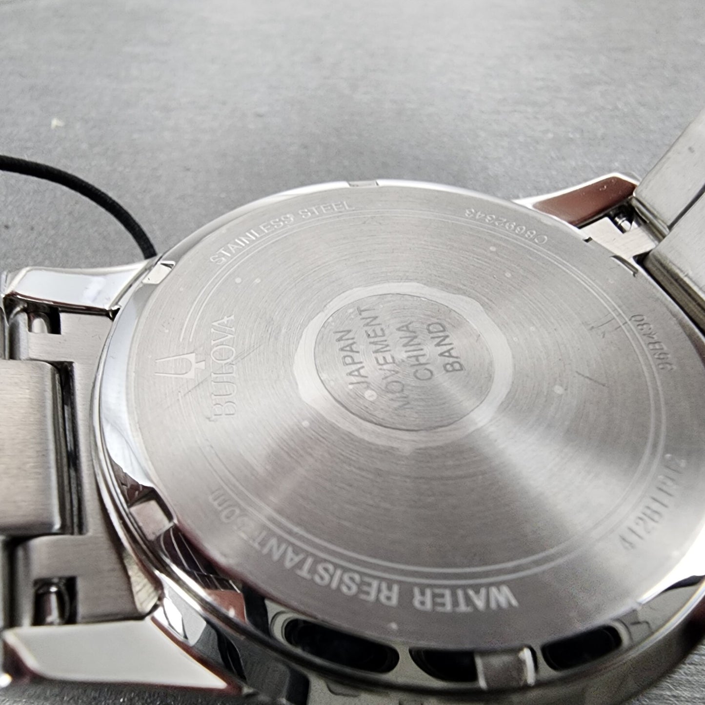 Close-up of Bulova stainless steel watch back case showing engravings and metal band.