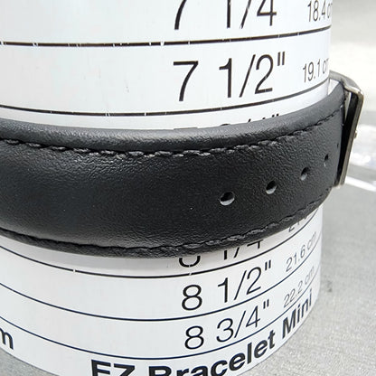 Black leather watch band on bracelet size measuring cylinder with size chart visible