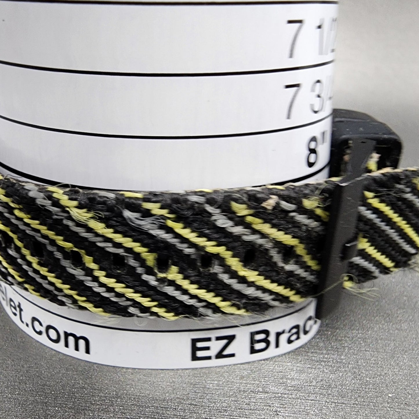 Black and yellow woven bracelet on measurement tool, EZ Bracelet sizer visible