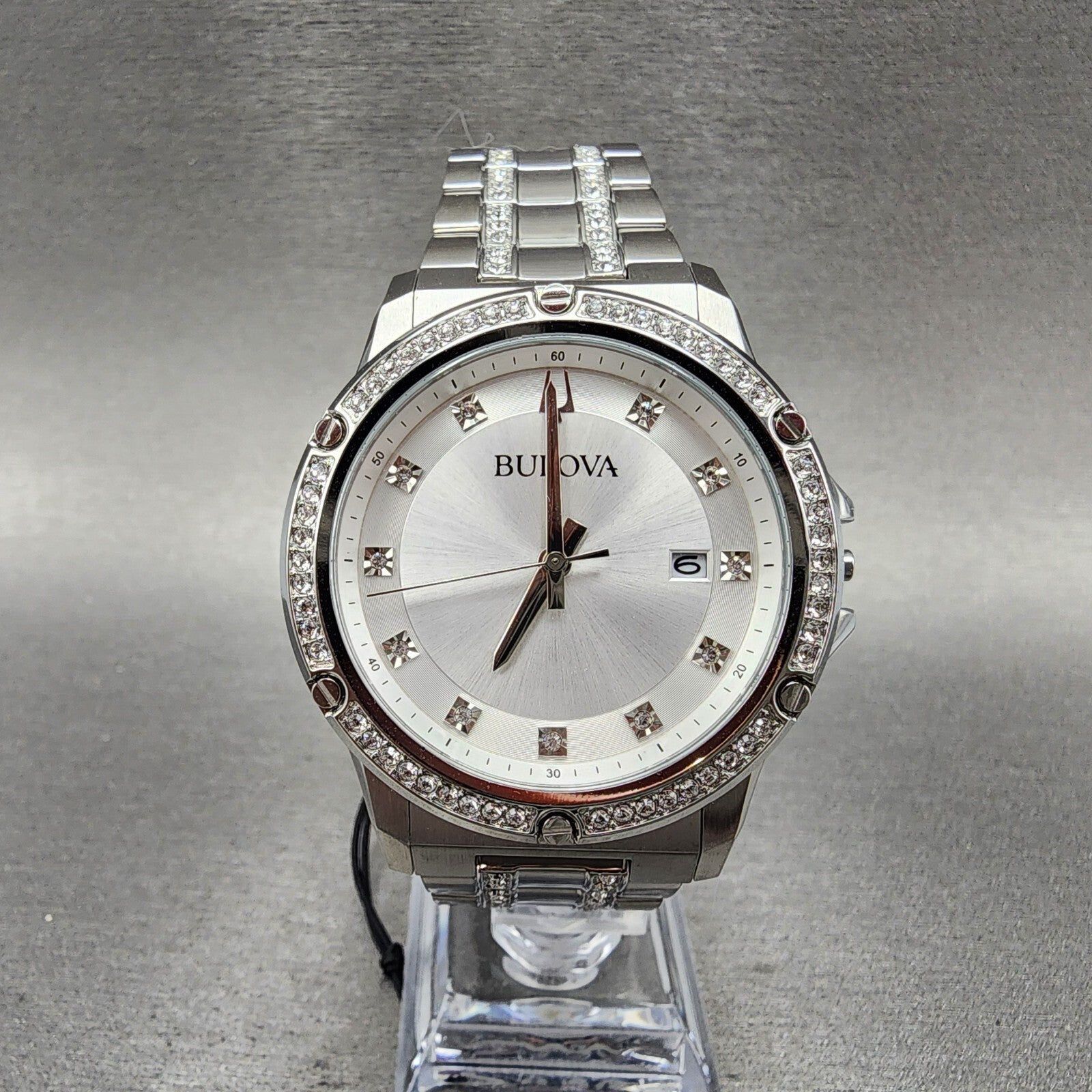 Bulova silver wristwatch with crystal accents, stainless steel band, and date display on stand