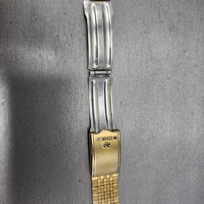 Seiko gold and silver metal watch clasp on a brushed steel background