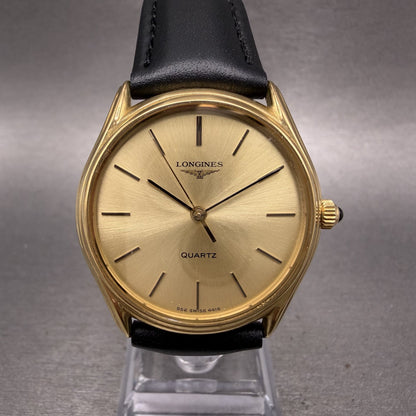 Longines gold quartz watch with black leather strap on gray background