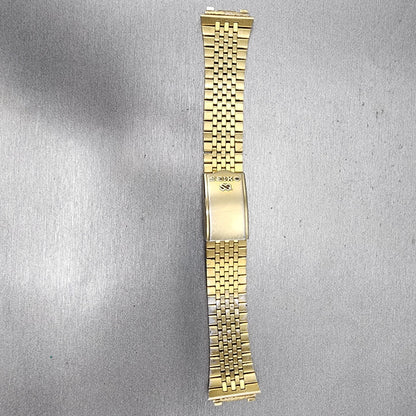 Seiko gold metal watch band with fold clasp on gray textured background