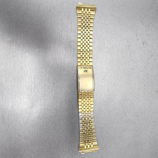 Seiko gold metal watch band with fold clasp on gray textured background