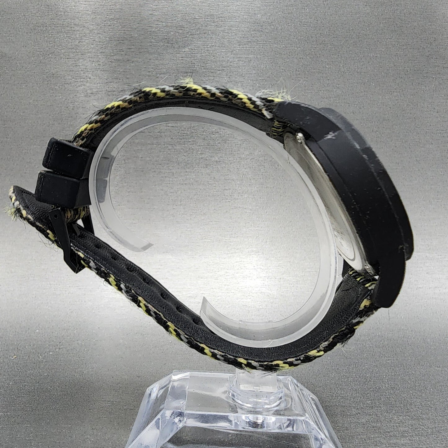 Black and yellow fabric strap wristwatch with plastic case on clear display stand