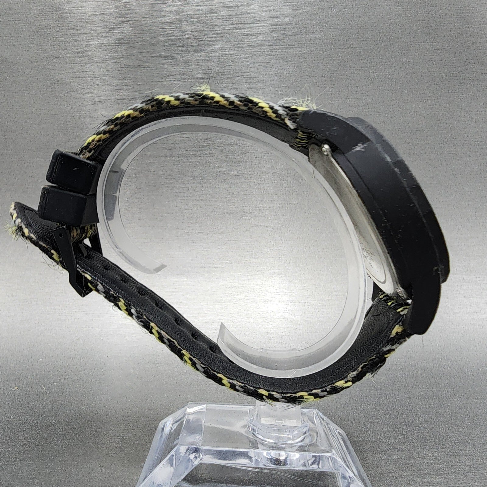 Black and yellow fabric strap wristwatch with plastic case on clear display stand