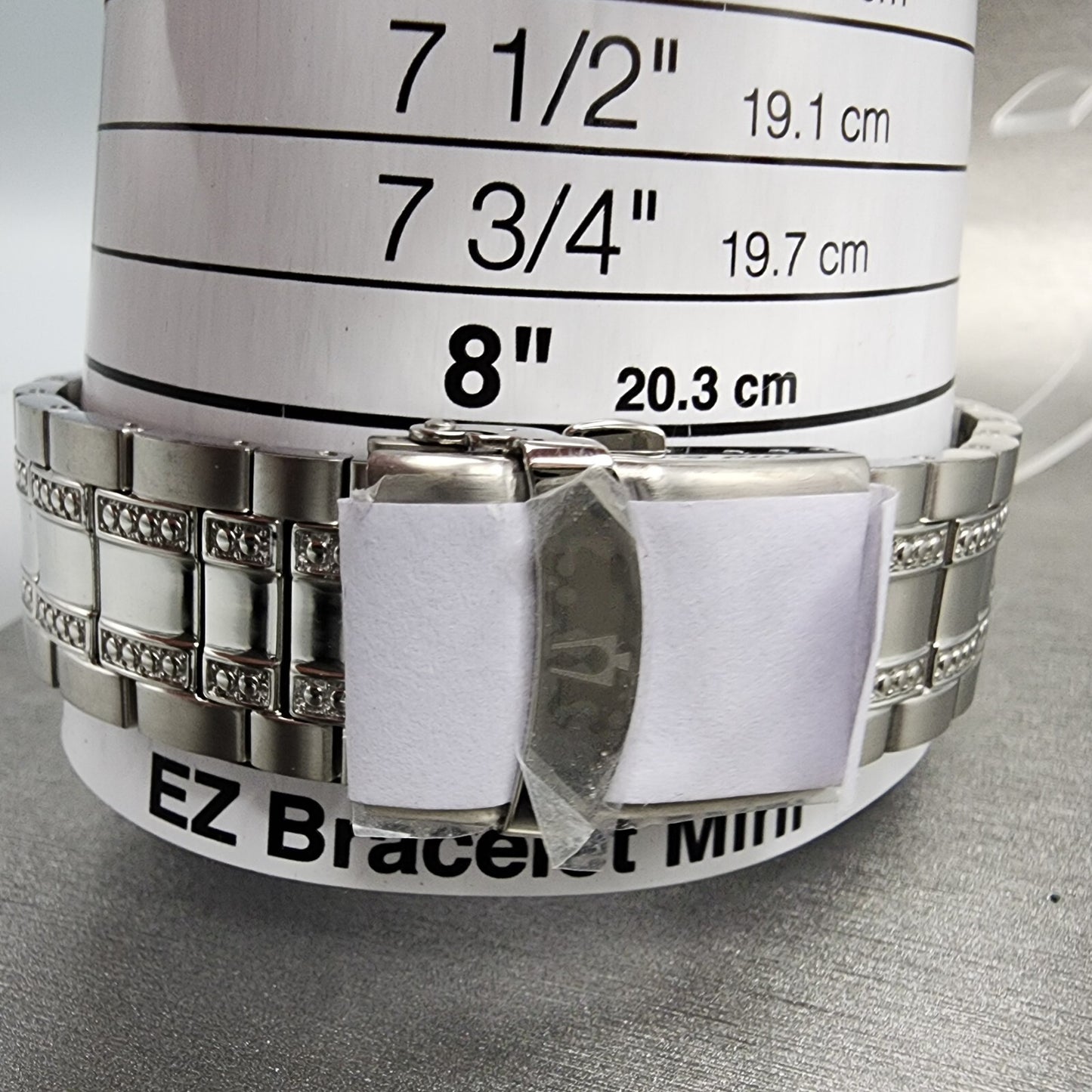 Stainless steel bracelet on wrist sizing tool showing 8 inch size marker, jewelry measuring guide