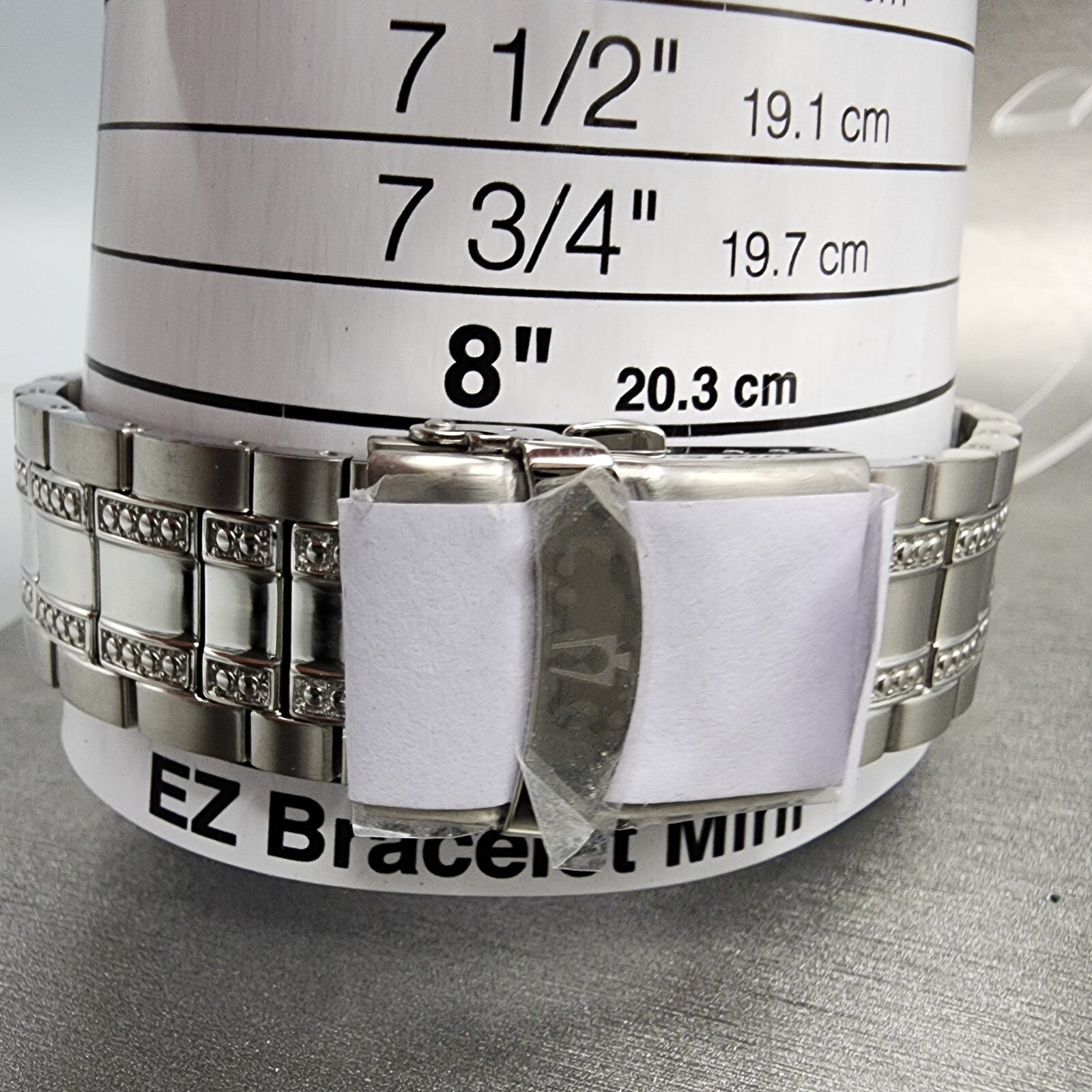 Stainless steel bracelet on wrist sizing tool showing 8 inch size marker, jewelry measuring guide