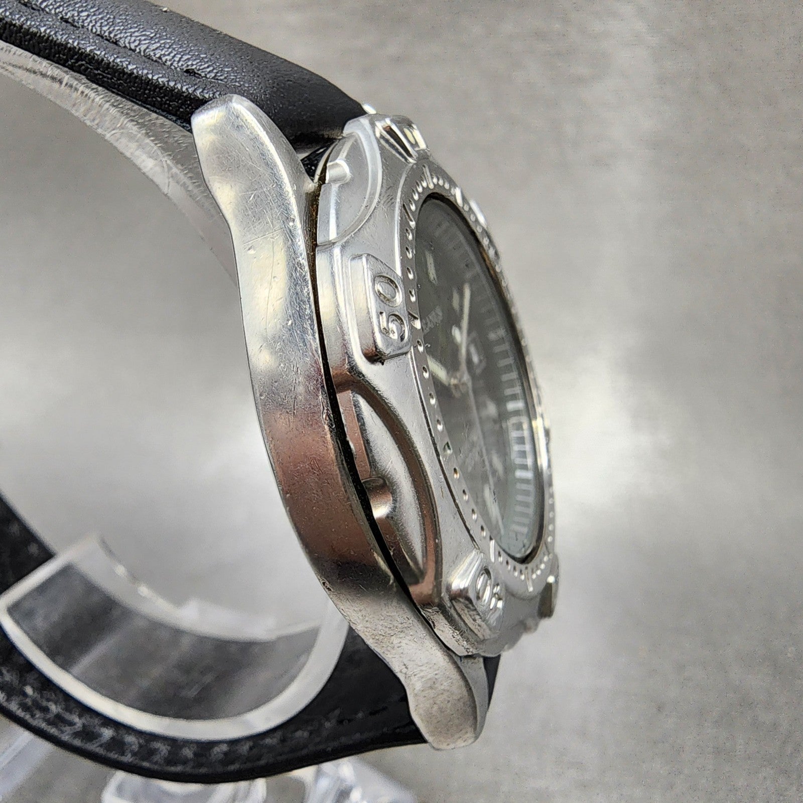 Close-up of a stainless steel wristwatch with black leather strap and engraved bezel